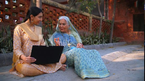 A beautiful young Indian using laptop with her grandma - dadi: success happiness topper girl. Old mother doing crochet feeling proud of her intelligent daughter - desi lifestyle modern villagers...