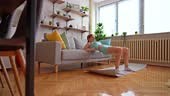 Beautiful young athlete slim woman working out in her home.