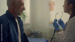 Woman therapist checking pulse elderly patient in clinic using stethoscope.