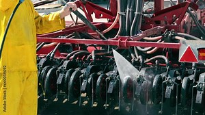 Washing of large-sized agricultural machinery. Cleaning the seeder after work in the field. A worker washes an agricultural machine with water under pressure.