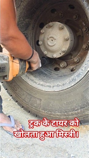 ट्रक के टायर को खोलता हुआ मिस्त्री।