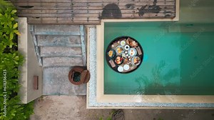 Top view of luxury floating breakfast in private pool. Special menu with floating pool tray for exotic summer vacations. Floating breakfast tray contains food and beverage is drifting in pool
