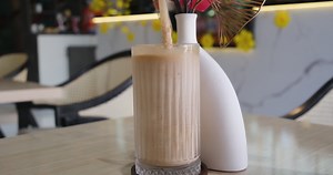 Chocolate milk pouring into a glass, splashing as it flows over, spilling on the table