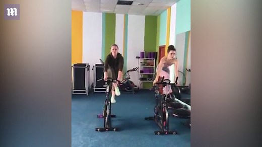 Fitness coach completes synchronized spinning routine with client