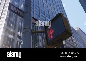 One Way street sign and a red pedestrian signal turn white, stand against tall glass buildings creating a simple urban scene that shows the modern architecture and street details of New York