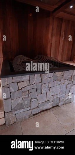 Vertical close up shows stacked stone facade, black metal rim, and twin arched steel rock baskets in warm low light, with slow move from wide to tight in an Alpine spa Stock Video Footage - Alamy