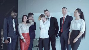 Team of businesspeople standing together in conference room and react to bad news as if just learned inconvenient information that upset them