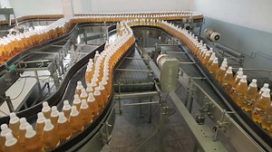 Rotating tower transporting large containers on industrial assembly line.
