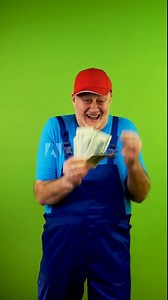 Senior repairman in overalls counts money from completed works and dancing.