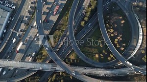 A top down bird's eye view of complex, interwoven highway and interstate on ramps and off ramps filled with traffic of driving cars