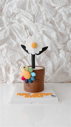 Simple, colourful, and oh-so-cute ✨ This miniature 4-inch flower pot cake features rainbow flowers made with @saracinodolci modelling paste fondant. A fun little project! | SugarArts Vancouver