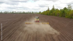 Sowing machine tractor sows seeds in an agricultural field. Aerial view. Spring sowing of the crop. Farmer on a tractor