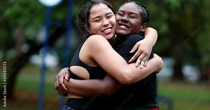 Diverse female friends hugging each other outside in park. Two girlfriends embrace