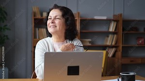 Confident stylish european middle aged senior woman using laptop at home. Stylish older mature 60s lady sitting at table looking at computer screen typing chatting reading writing email