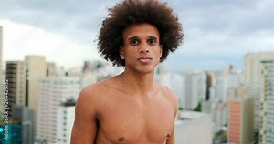 Shirtless young handsome mixed race african man standing on top of rooftop