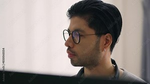 A close-up profile of an Asian male programmer deeply focused on his work, highlighting the intensity and concentration required in software development.