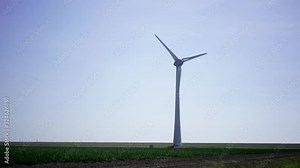 Metallic huge windmill in rural field area covered with wind blowing proving clean ecological alternative power from nature. Alternative electricity generation