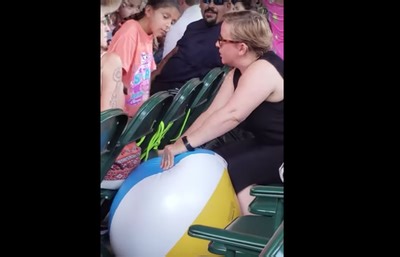 Woman pops beach balls being thrown around a kids concert