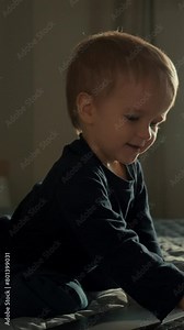 Sweet toddler learns to type text on keyboard of modern laptop. Curious child gets new skills of using gadget in bedroom closeup slow motion Vertical footage.