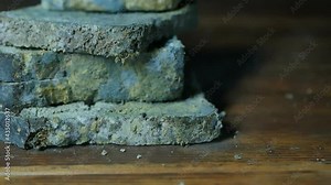 falling moldy bread on a wooden table. Pieces of moldy bread emit green dust when dropped. Slow motion. Close-up