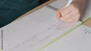 left-handed schoolchild doing homework, child writes English in notebook, assignments involving English language exercises, acquisition, vocabulary building in school setting, Bilingual Education