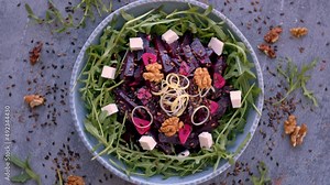 Baked beetroot and arugula salad with garlic, walnuts, cheese, linseed and leek. Top view table spin. Stock Video