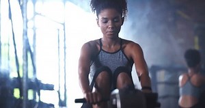 Woman, rowing machine and gym training, thinking of fitness or tired for muscle workout, challenge and breathing. Strong African person with pull cable or equipment and serious face for health goals