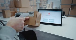 Postal Service Employee Scans Code on Cardboard Box with Barcode Scanner, Checks Parcel Information. Tablet Computer Screen Shows Delivery Tracking App to Monitor Package Routing to Client. Close Up.