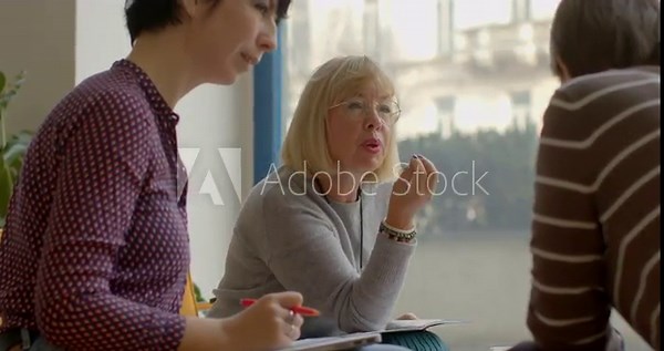 Female employee at insurance company conducts consultations for clients, providing detailed information on various insurance policies and options available. Woman 60 years old assists clients, talking