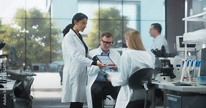 Modern Medical Laboratory: Scientists Working Together on a Research Project. Male and Two Young Women Talking About Vaccine Development Methods and Biotechnology Breakthroughs. Cinematic Footage