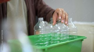 Close-up shot hand collecting and separating recycling plastic bottles putting into recycle garbage box . Sorting waste plastic bottles a trash bin at home.