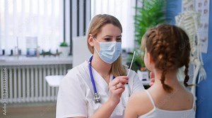 Young female doctor taking nasal swab test from little girl in clinic.