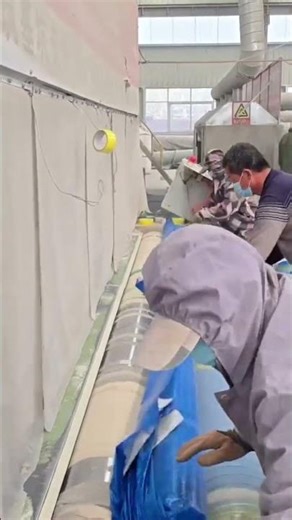 The rolling up a tarpaulin using a special rolling device is being tidied up by several workers