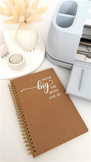Sarah on Instagram: "✨Dream Big Notizbuch✨ [Werbung | Kooperation mit Cricut] Ein kleiner Reminder auf meinem Schreibtisch: dream big and never give up. Ich habe dieses schlichte Kraft-Notizbuch mit meinem Cricut Maker 3 von @cricut_de und weißer Vinylfolie individualisiert – eine ganz einfache Möglichkeit, aus einem Basic etwas Persönliches zu machen. Nutzt ihr euren Cricut eher für Papeterie oder eher für Deko-Projekte? #cricutyourideas #sarsicreations #cricut"