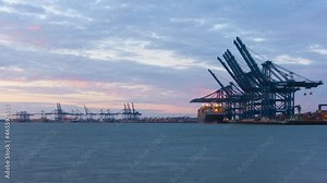 Felixstowe, United Kingdom - October 24 2021: Sunset timelapse as container cargo is loaded on-board ships at the Port of Felixstowe, amid a major worldwide supply chain crisis