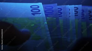 verification of counterfeit money in a ultraviolet. UV check of Euro banknotes