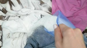 Woman pouring washing powder on clothes laundry textile, top view, slow motion