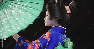 4K beautiful Japanese geisha dancing on stage and posing for the camera with an umbrella, in slow motion