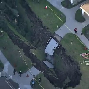 A nearly 100-foot sinkhole opened up in the middle of a condo complex off Imperial Highway in La Habra, swallowing trees. An underground flood control channel collapsed, causing the ground above to fall, police said. No one was injured. Details: http://on.ktla.com/lGJVM | KTLA 5 News