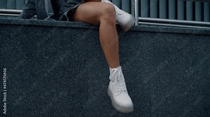 Female model legs sit posing in urban building city downtown.
