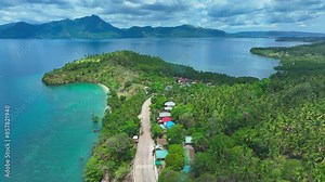 Slow drone flyover tropical Biliran Island with turquoise bay during sunny day in Philippines. Houses at carigara bay in exotic landscape with palm trees.