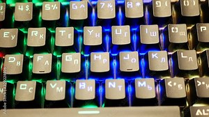 Multi-colored keyboard. The keyboard backlight shimmers in different colors. Wiring towards the camera. RGB keyboard. close-up. View from the face. Hacker. typing on a modern trendy keyboard. Cybercri