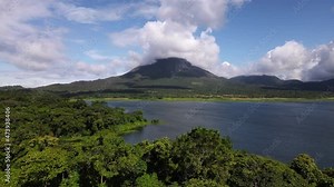 Long video of Arenal volcano behind Costa Rica's largest man made lake. Gigantic world famous landmark last erupted in 2010. Lush leafy rainforest captured by a professional 4k drone.