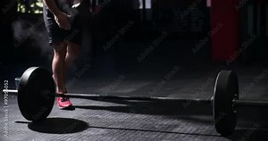 Bare chested man weightlifting barbells in a gym