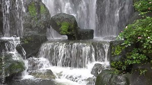 Beautifully decorated artificial waterfall with green plants, in a traditional Asian setting, in the garden of a temple in Taipei, Taiwan