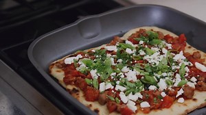 A new use for the Anolon Accolade Grill Pan – the crust for this savory pizza is grilled on both sides to acheive the perfect char, making it one incredible vessle for a savory lamb, feta, and sumac topping. Get the recipe: http://bit.ly/2Oyv3VI | Anolon