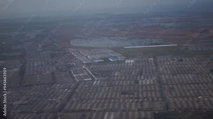 A view from an airplane window during takeoff or landing, showing the landscape below