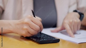 A person is writing on a tablet with a pen. The tablet is a calculator and the person is using it to write