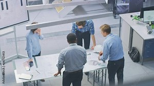 In Busy Engineering Facility: Diverse Group of Engineers, Technicians, Specialists Working on Design for Industrial Engine Prototype. Professionals Talk, Work with Drawings, Use Computers. High Angle