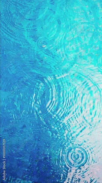 Raindrops fall into outdoor swimming pool vertical video 4K. Aqua blue water surface with ripples. Low season vacation in tropical resort. Beginning of torrential rainstorm. Drops of rain from above